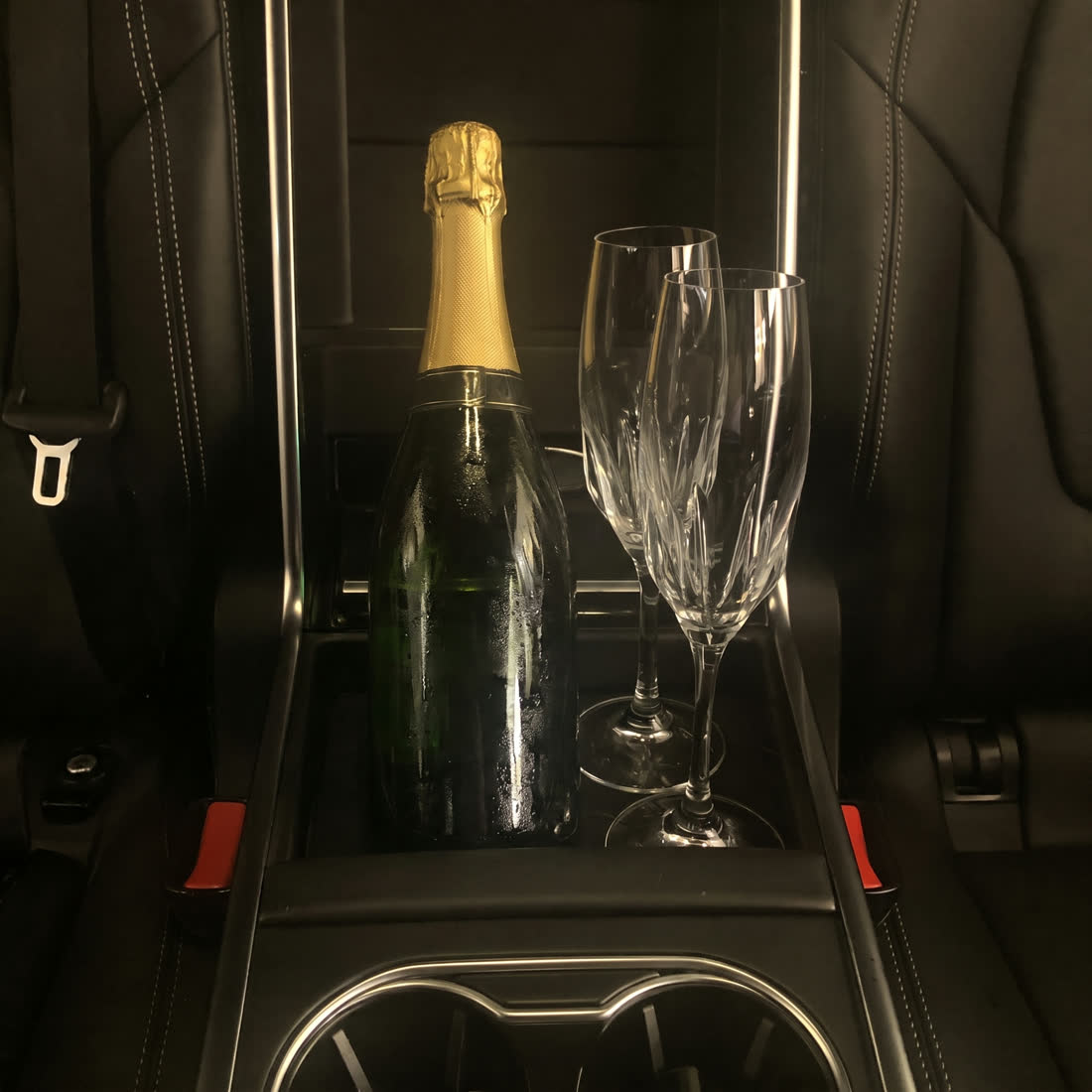 Chilled champagne and two crystal flutes in a black leather rear console